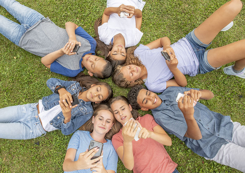 Multiethnic group of young teenagers enjoy a summer day or recess outside together.